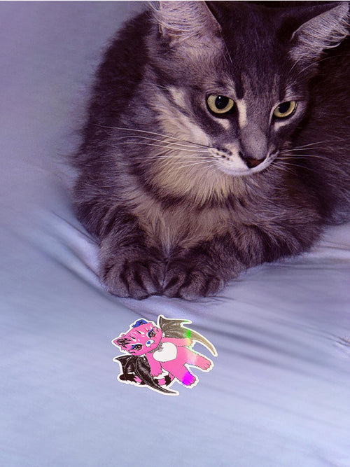 Real cat posing with a holographic Tommi the Batcat sticker; pink gothic kawaii vinyl decal